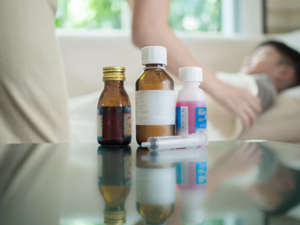 Baby medicine with sick child boy lying in sofa with a fever background, resting at home