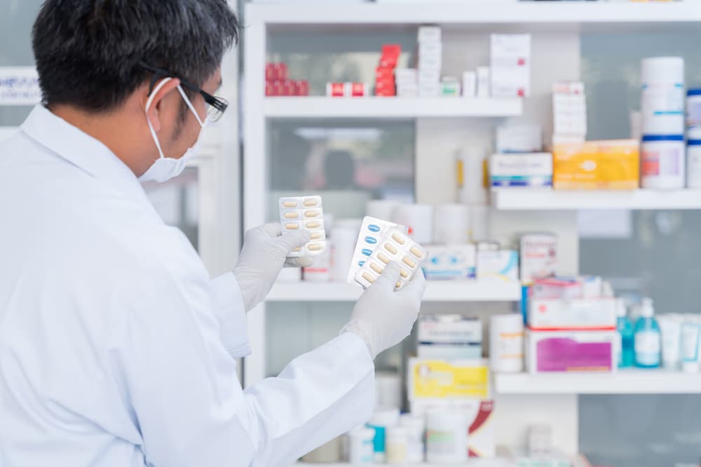 Pharmacist holding medicine capsule pack in pharmacy drugstore