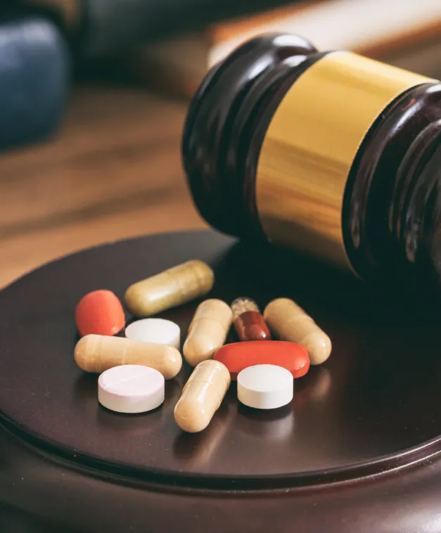 A judge’s gavel beside several pills, symbolizing legal action over drug-related injuries