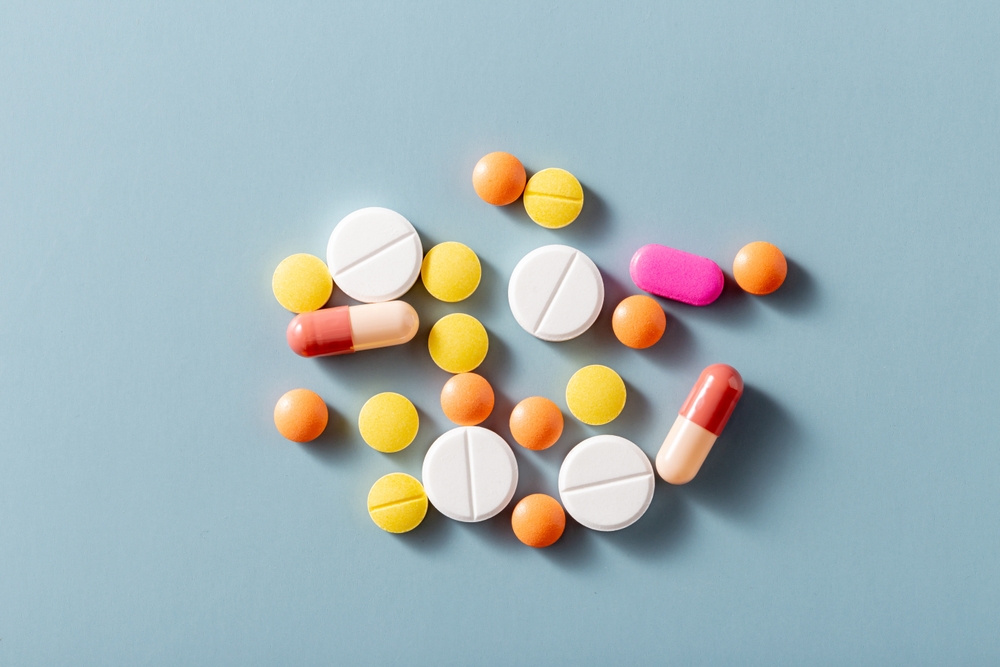 Various colorful pills and tablets on a blue background symbolizing medications that can trigger Stevens-Johnson Syndrome
