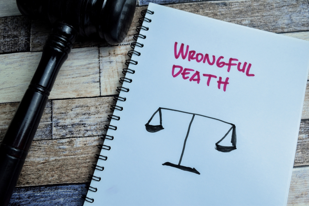 Notebook with the words ‘Wrongful Death’ and a justice scale sketch next to a courtroom gavel