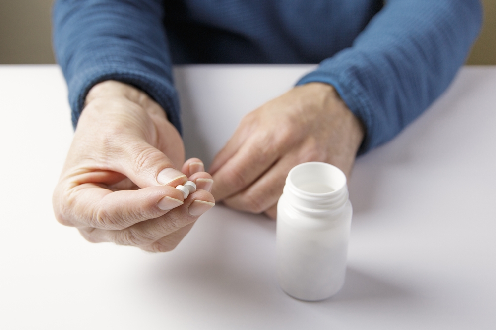 Close-up of a person holding prescription pills next to a white bottle, representing medication linked to Stevens-Johnson Syndrome lawsuits.